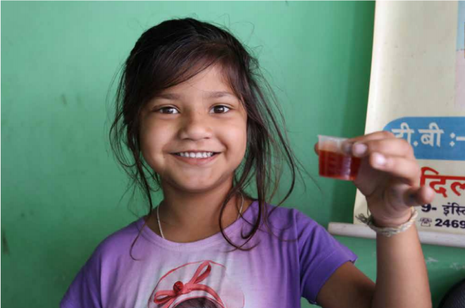 Girl holding dissolved child-friendly treatment in small cup. Image attributed from TB Alliance (2017)