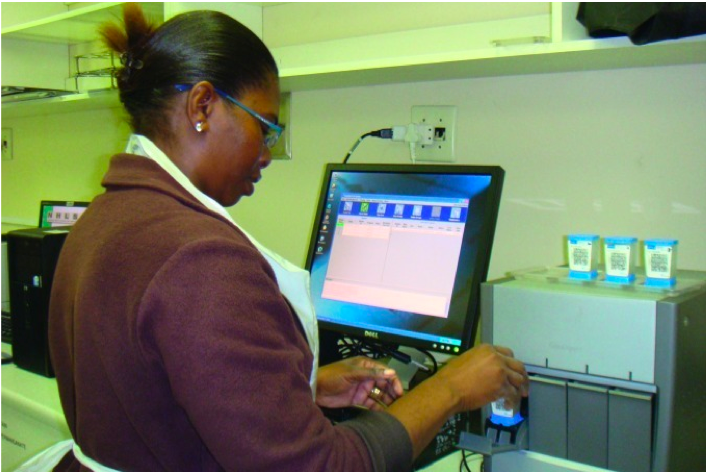 Technician in South Africa inserts cartridge containing a specimen into the Xpert machine for testing